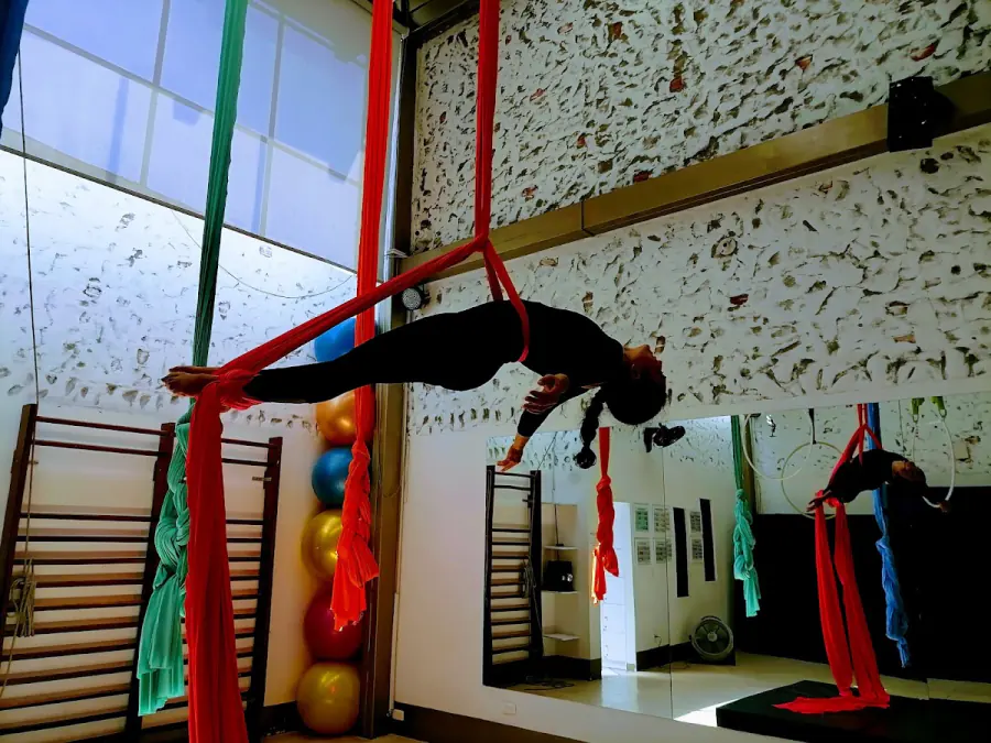 Alumna haciendo una figura en las telas rojas